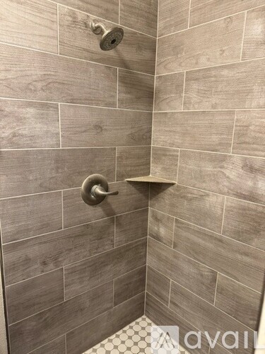 A shower with a tiled wall and a shower head.