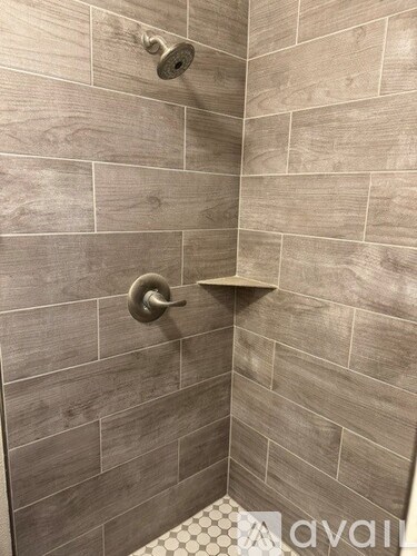 A shower with a tiled wall and a shower head.