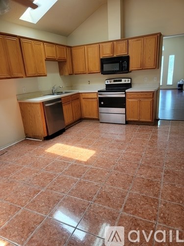A kitchen with brown cabinets and tile flooring.