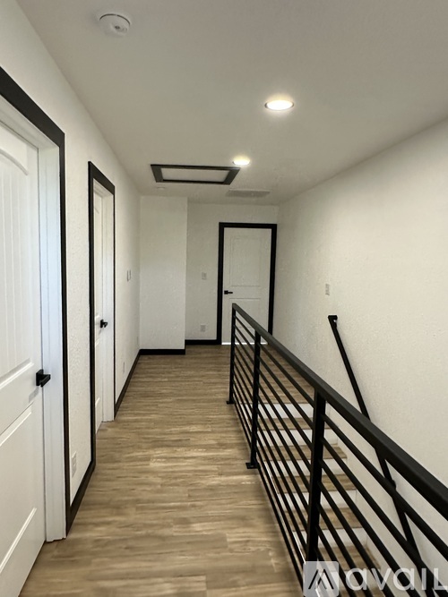 A long hallway with a wooden floor and white walls.