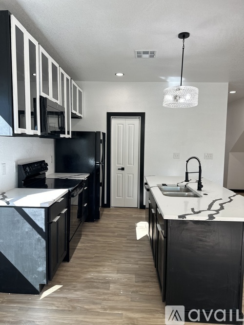 A kitchen with black and white cabinets and a black refrigerator.