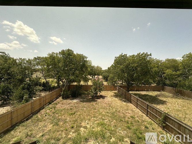 A backyard with a fence and trees.