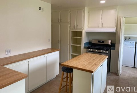 A kitchen with white cabinets and a wooden counter.