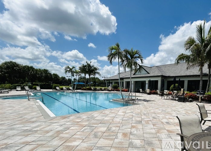 A large outdoor swimming pool surrounded by palm trees and lounge chairs.