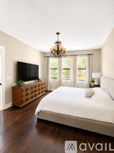 A bedroom with a large bed, a tv, and a chandelier.