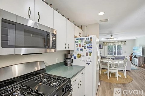 A kitchen with a stove top oven and a refrigerator with magnets on it.