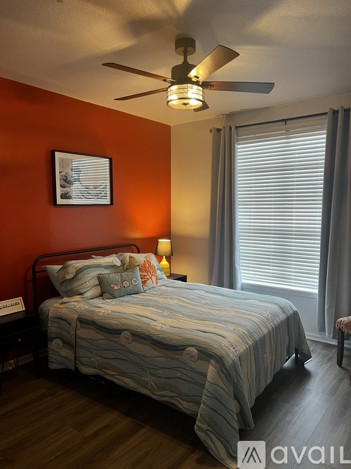 A bedroom with a bed, a ceiling fan, and a window with blinds.