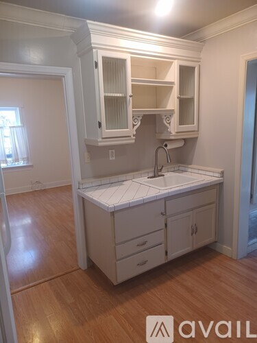 A white kitchen with wooden floors and a sink.