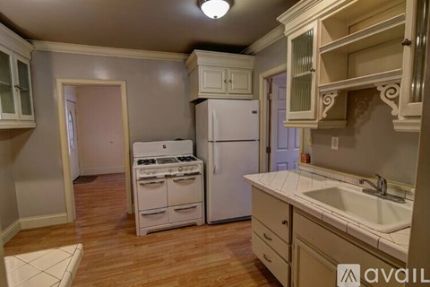 A kitchen with a white stove and cabinets.