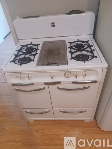 A white gas stove with four burners and two ovens.