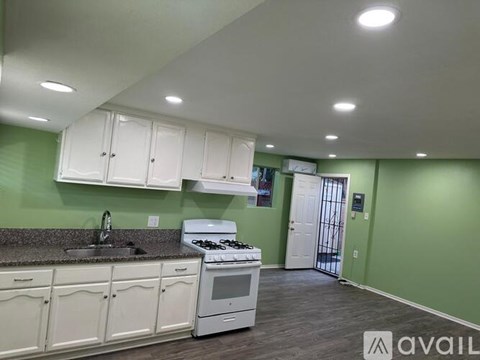 A kitchen with white cabinets and a white stove top oven.
