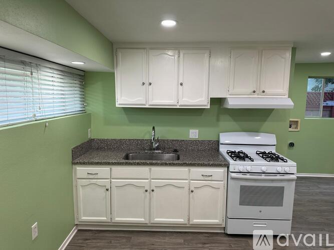 A kitchen with green walls and white cabinets.