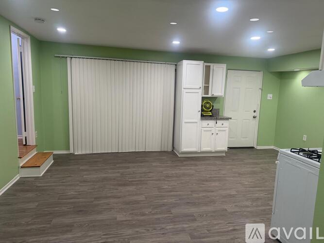 A kitchen with green walls and a white cabinet with a yellow clock on it.