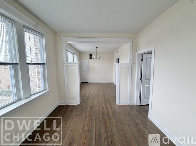 A spacious room with wood flooring and white walls.