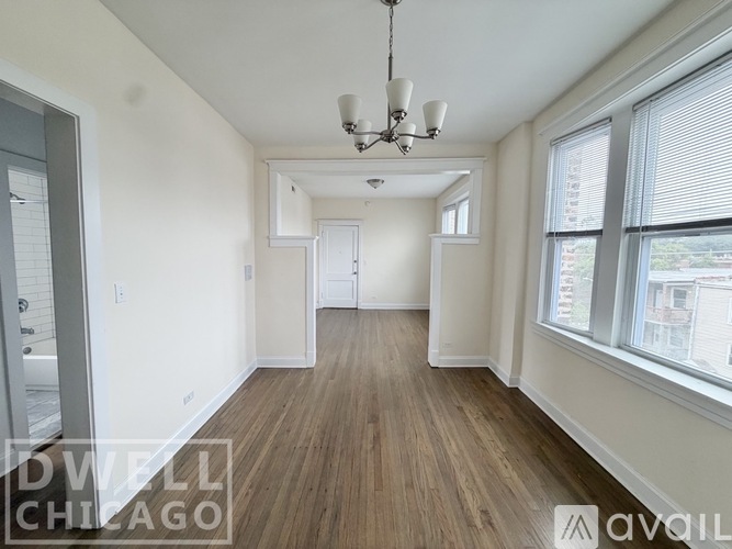 A room with wood flooring and a chandelier.