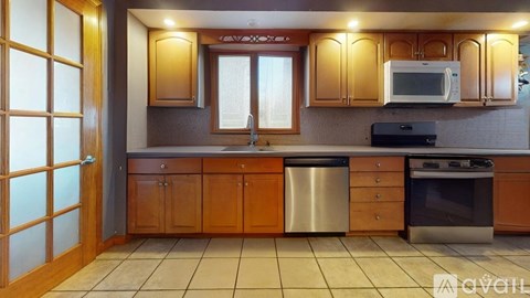 A kitchen with wooden cabinets and a tiled floor.