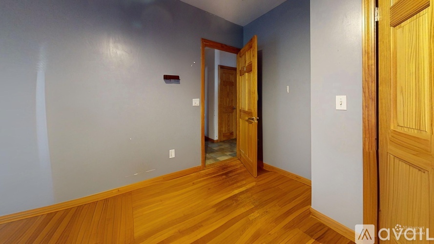 A room with wooden floors and a door leading to another room.