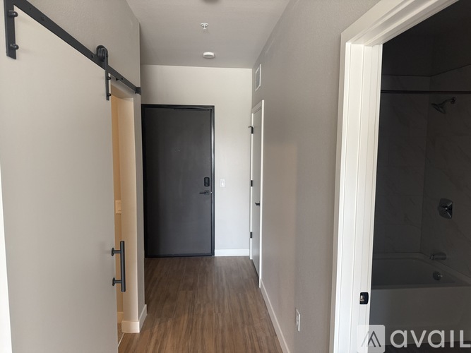 A hallway with a black door and a white wall.