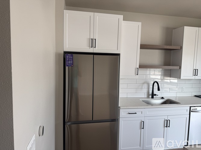 A kitchen with a refrigerator, sink, and cabinets.