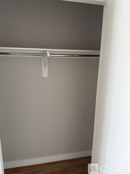 A white closet with a grey wall and wooden floor.