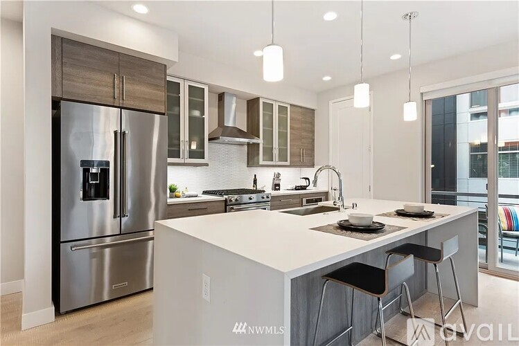 A modern kitchen with a stainless steel refrigerator and a white island.