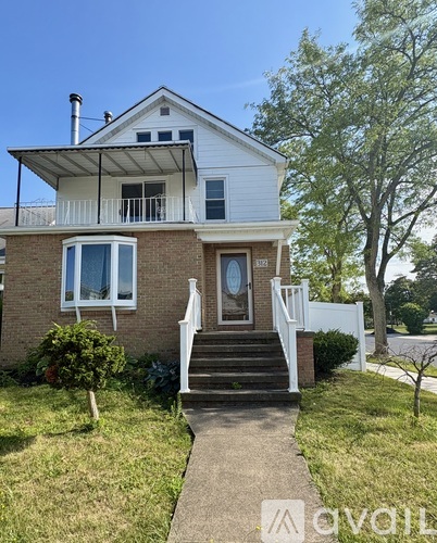 A house with a white roof and a brick facade has a small front porch.