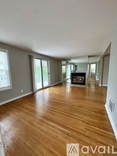 A spacious room with wooden flooring and a fireplace.