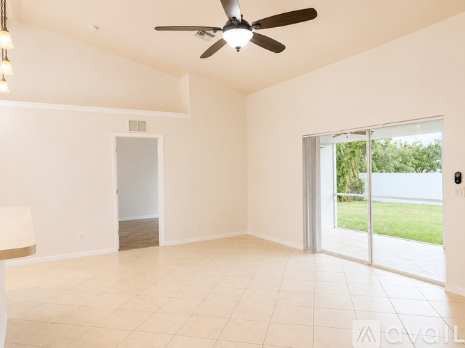 A spacious room with a ceiling fan and sliding glass doors.