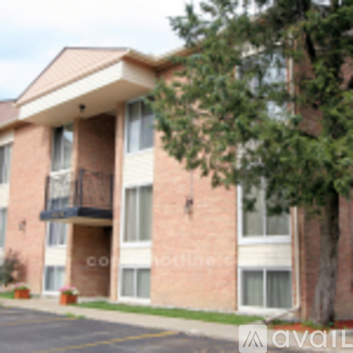 A brick building with a balcony and a tree in front.