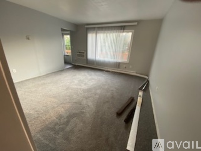 A room with a carpeted floor and a window with blinds.