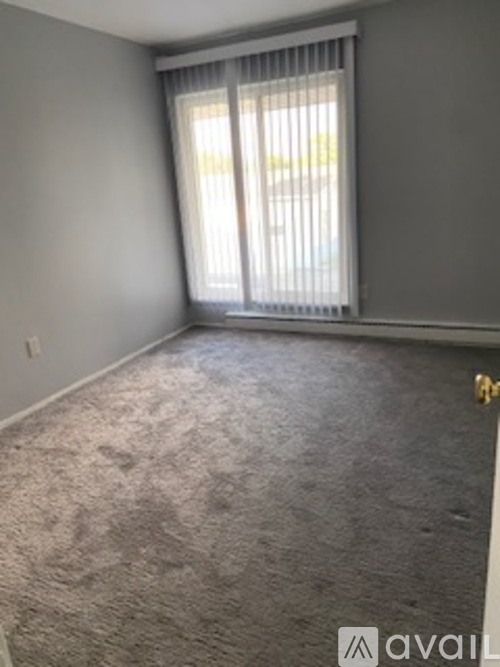 A room with a carpeted floor and a window with blinds.