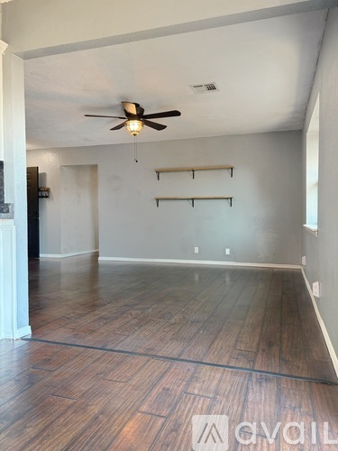 A room with a ceiling fan and wooden flooring.