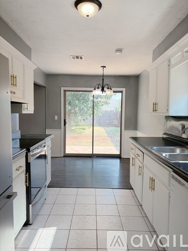 A kitchen with white cabinets and a black countertop.