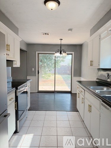 A kitchen with white cabinets and a black countertop.