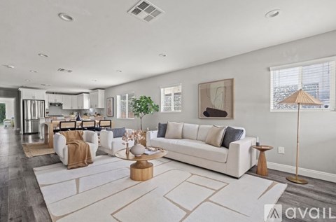 A spacious living room with a white sofa set and a wooden coffee table.