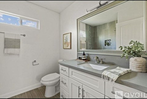 A bathroom with a toilet, sink, and mirror.