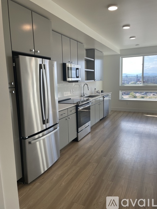 A modern kitchen with stainless steel appliances and wooden flooring.
