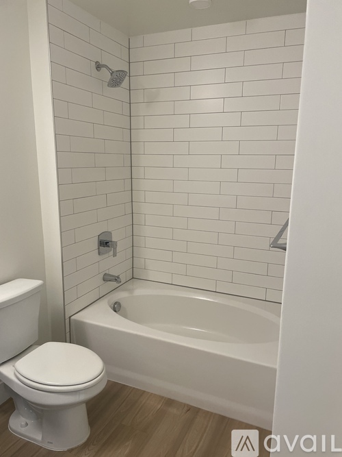 A white toilet sits next to a white bathtub in a bathroom with white tiles.