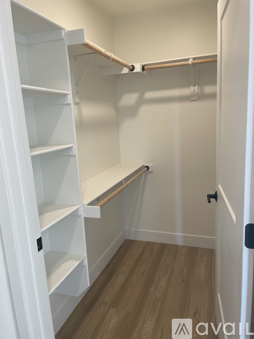 A white closet with shelves and a wooden floor.