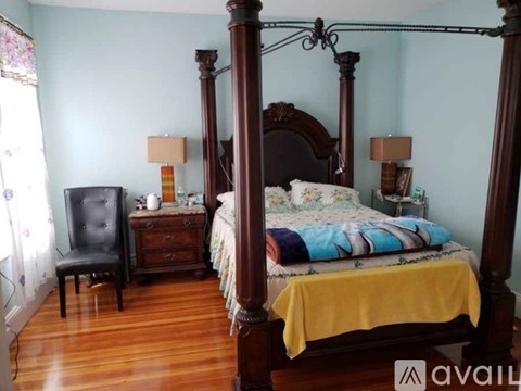 A bedroom with a four poster bed and a chair.