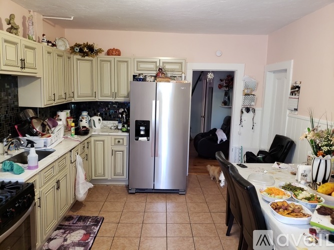 A kitchen with a refrigerator, table with food, and a dog.