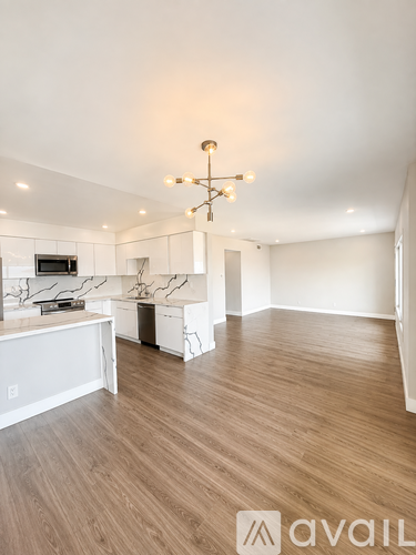A modern kitchen with wooden floors and a chandelier.