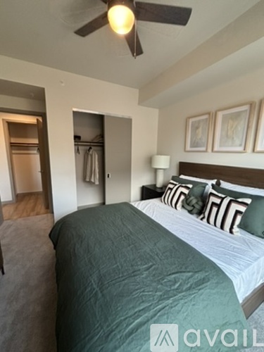 A bedroom with a bed, pillows, and a ceiling fan.