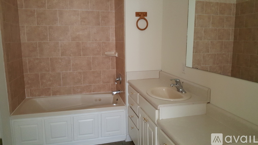 A bathroom with a tub, sink and mirror.