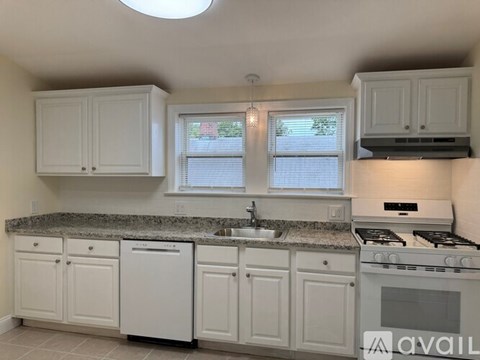 A kitchen with white cabinets and a granite countertop.