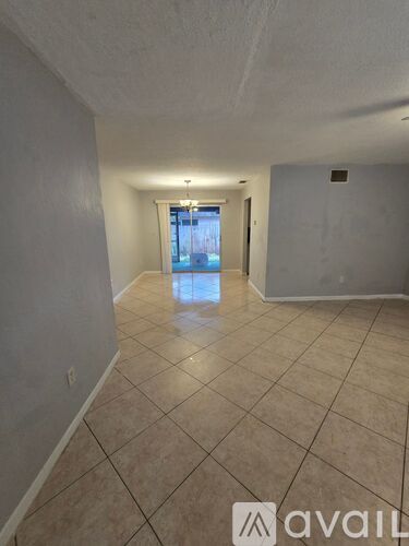 A spacious room with tiled flooring and a doorway leading to another room.