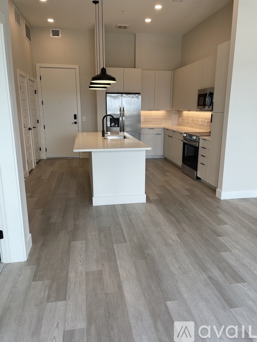 A kitchen with a white island and wooden flooring.