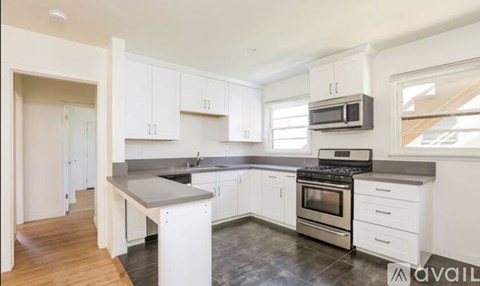 A modern kitchen with white cabinets and stainless steel appliances.