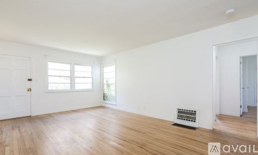 A room with wooden floors and a window with blinds.
