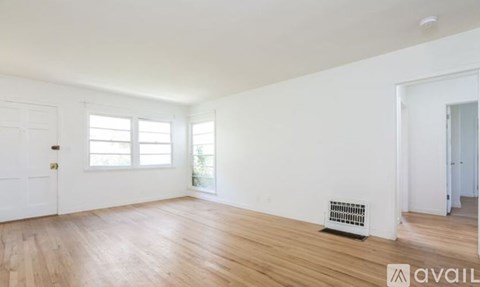 A room with wooden floors and a window with blinds.